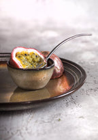 Assiette en grès émaillé brun gris moucheté avec fruit de la passion coupé