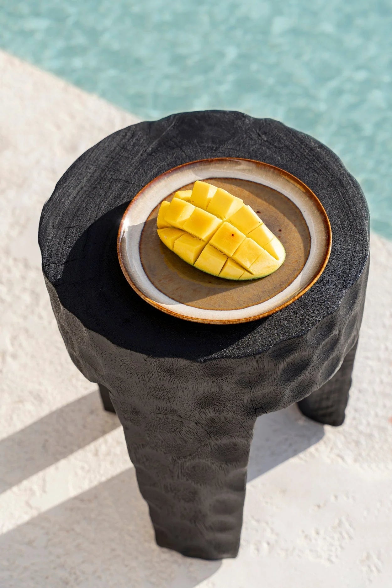 Mangue jaune éclatante coupée en cubes sur assiette en grès émaillé brun artisanal