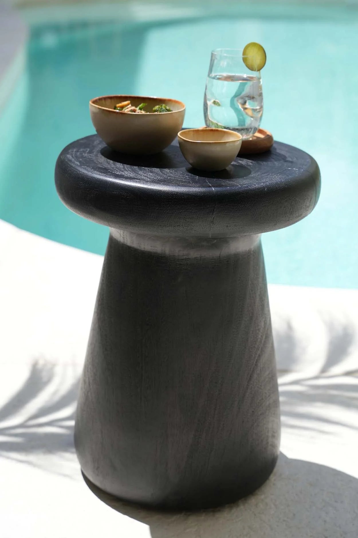 Table basse en pierre grise texturée, plateau rond et base effilée