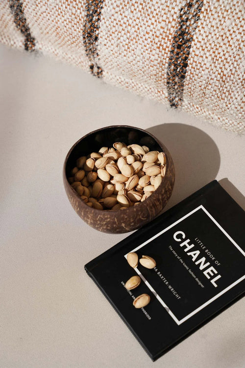Bol en noix de coco naturelle brun foncé forme ronde rempli de pistachios