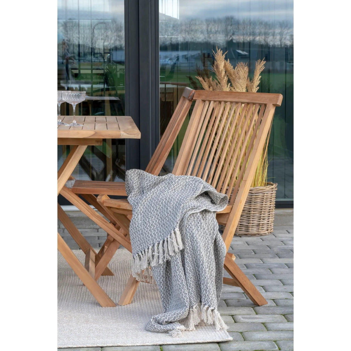 Couverture tissée gris clair à motif géométrique blanc sur chaise pliante en teck
