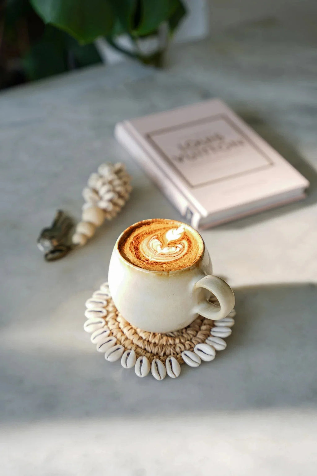 Tasse en céramique avec latte art sur un sous-verre rond en raphia et coquillages