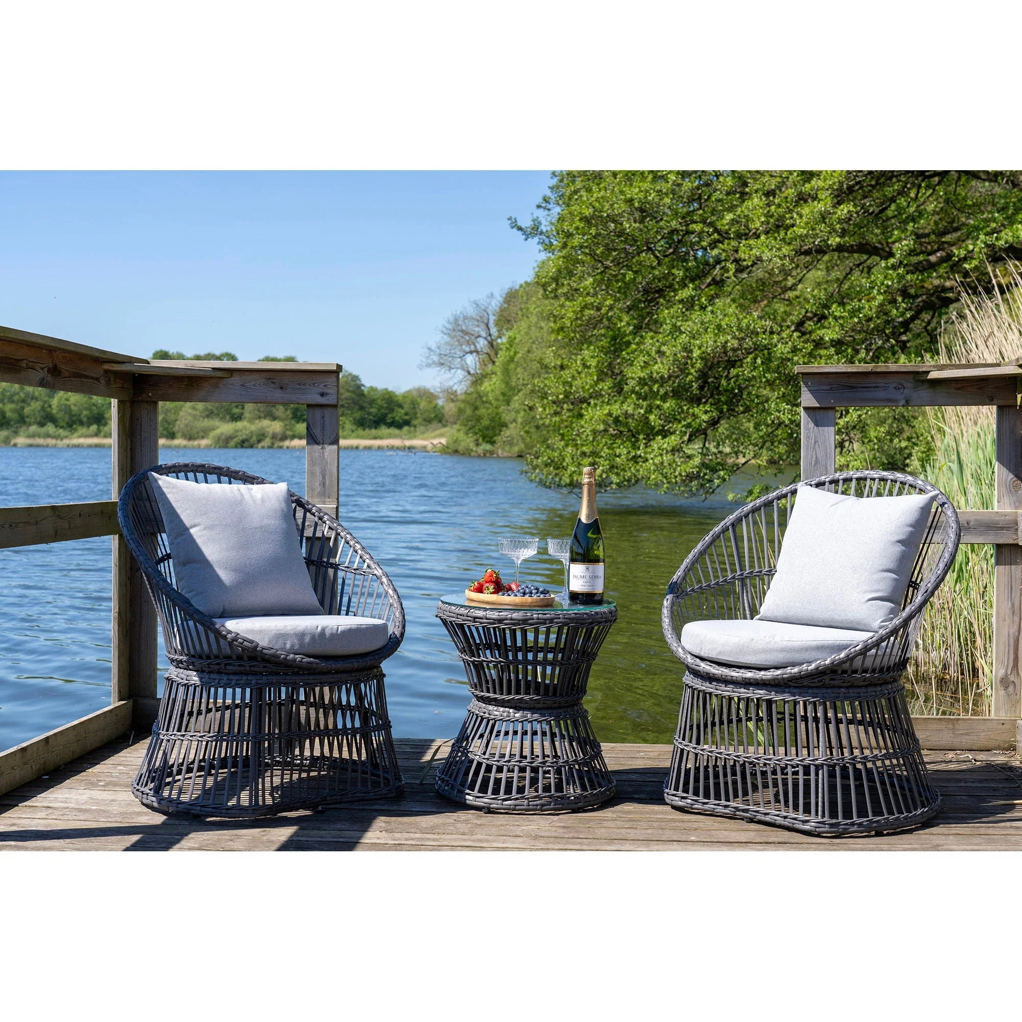 Ensemble lounge en rotin gris foncé avec coussins gris clair et table ronde