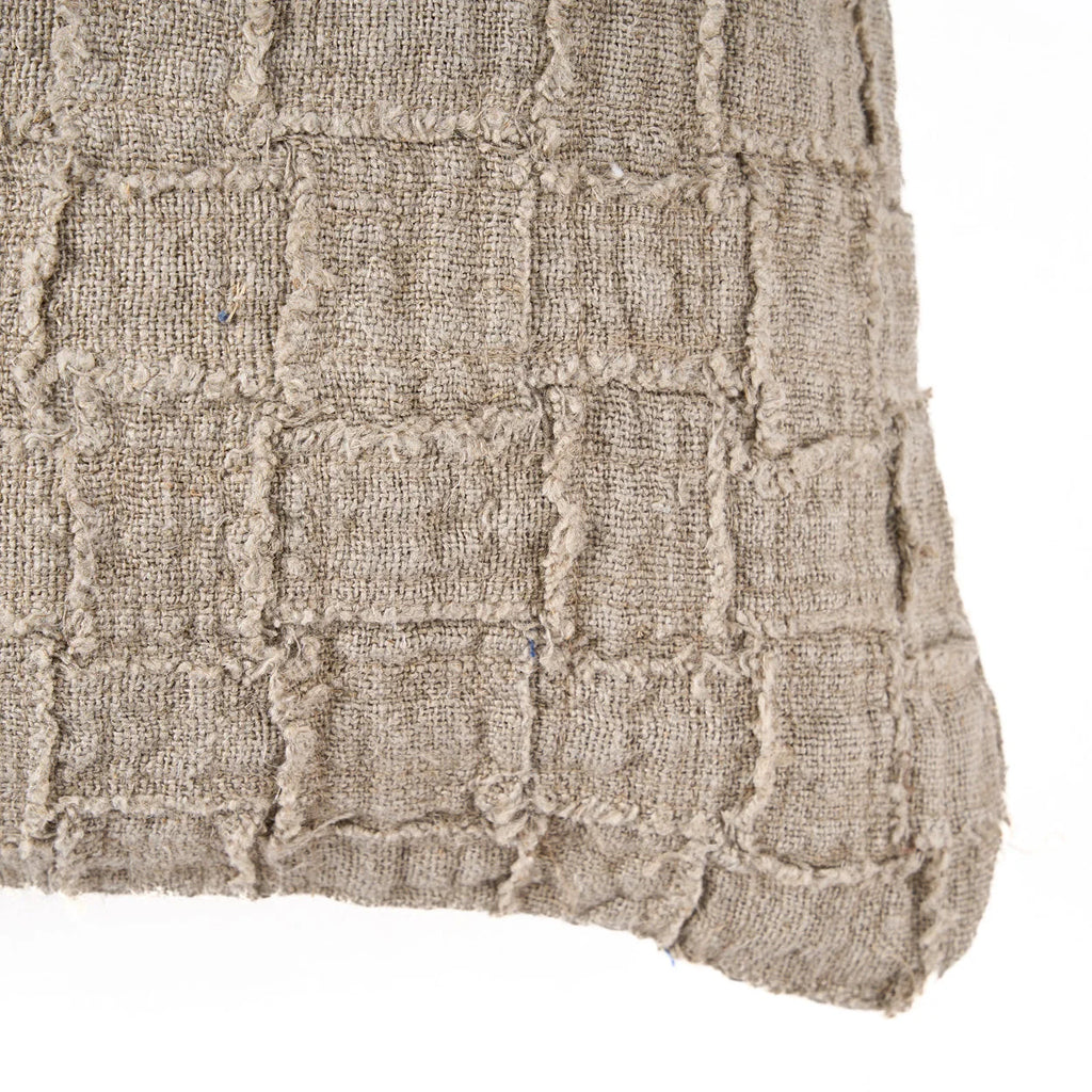 Housse de coussin lin beige à carreaux relief contre mur rustique