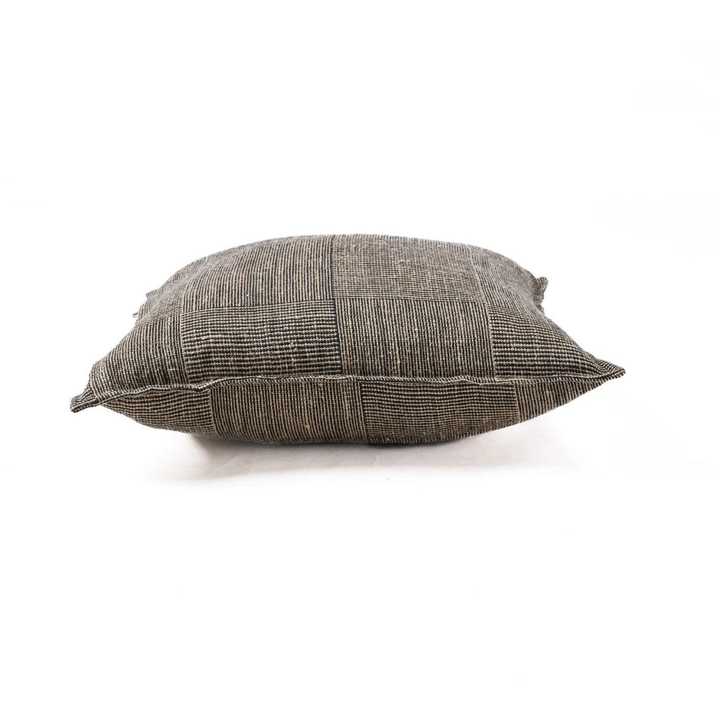 Coussin artisanal en lin tissé noir et beige motif damier sur canapé crème