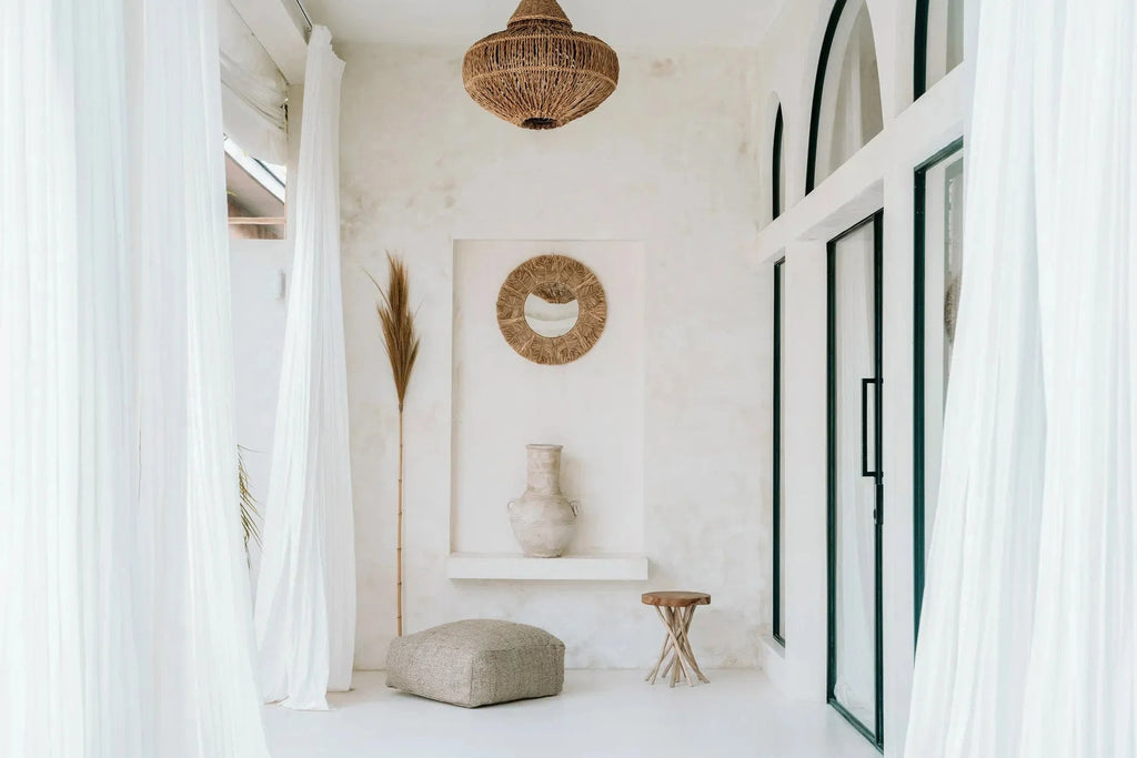 Miroir mural rond en raphia naturel et coquillages dans une pièce blanche minimaliste boho