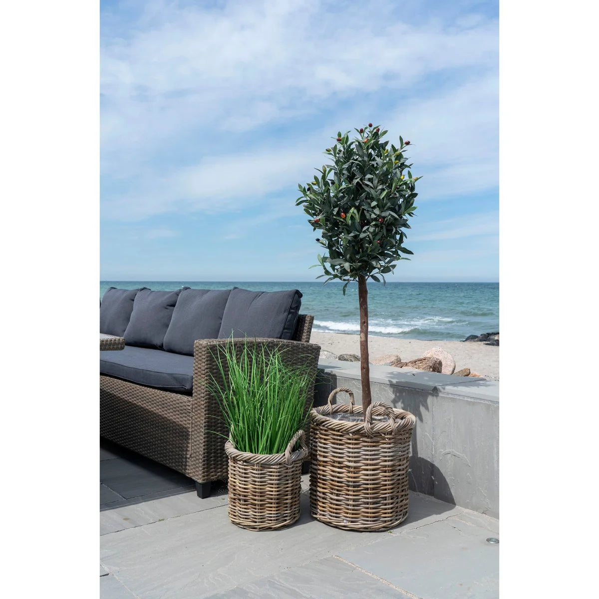 Panier rond en rotin tressé gris avec anse, contenant verdure