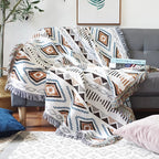 Plaid aztèque à franges posé sur un canapé avec des motifs ethniques colorés