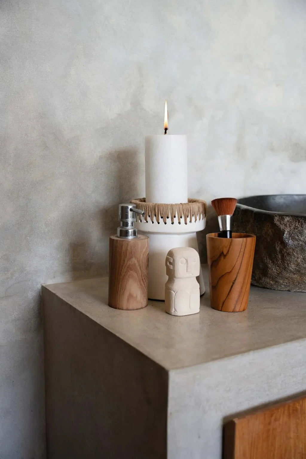 Bougie cylindrique blanche allumée dans porte-bougie en terre cuite blanche à finition raphia naturel H16 cm