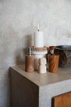 Bougie cylindrique blanche allumée dans porte-bougie en terre cuite blanche à finition raphia naturel H16 cm