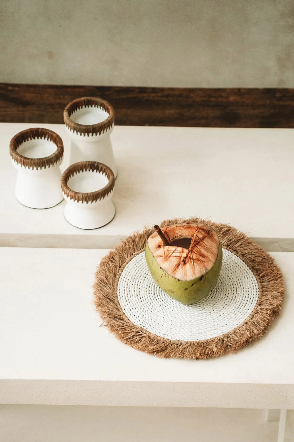 Cocotier frais avec boisson dans un set de table rond en raphia et herbe marine blanc naturel