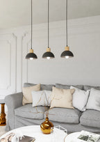 Trois suspensions linéaires en métal noir et bois au-dessus d’un sofa gris