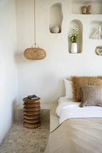 Suspension ovale en rotin naturel ajouré dans une chambre moderne avec table de nuit en bois
