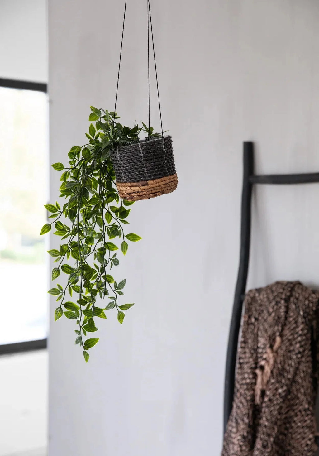 Plante suspendue en faux feuillage dans un panier tressé noir en feuille de bananier