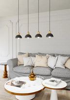 Suspension scandinave noire et bois 4 lumières en métal au-dessus d’un sofa gris