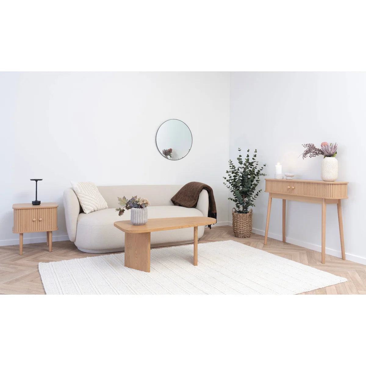 Canapé beige clair capitonné avec accoudoirs ronds et table basse ovale en bois naturel 50x100 cm