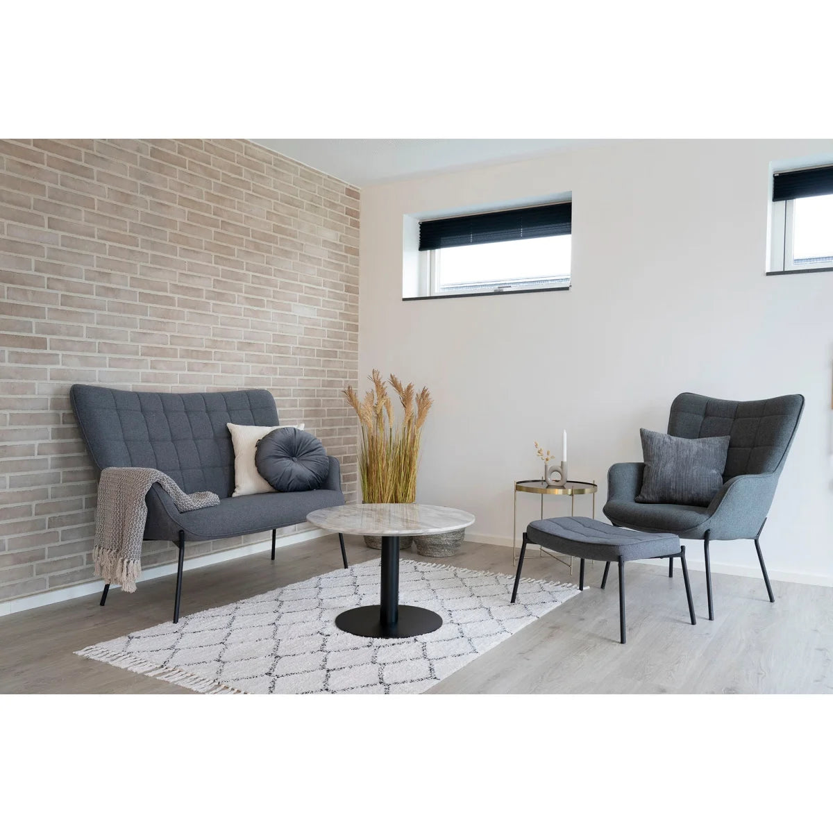 Canapé gris moderne capitonné, pieds métal noir, plaid texturé, table basse marbre ronde Ø70 cm pied central noir